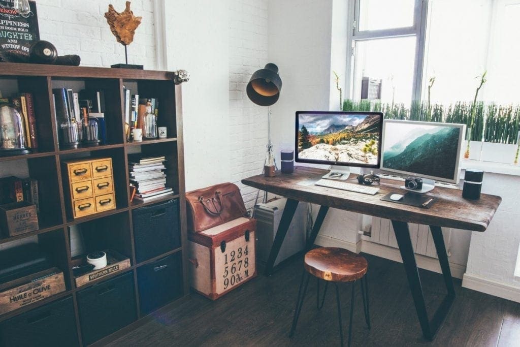 Small Desk in corner of small space with a computer and bookshelf