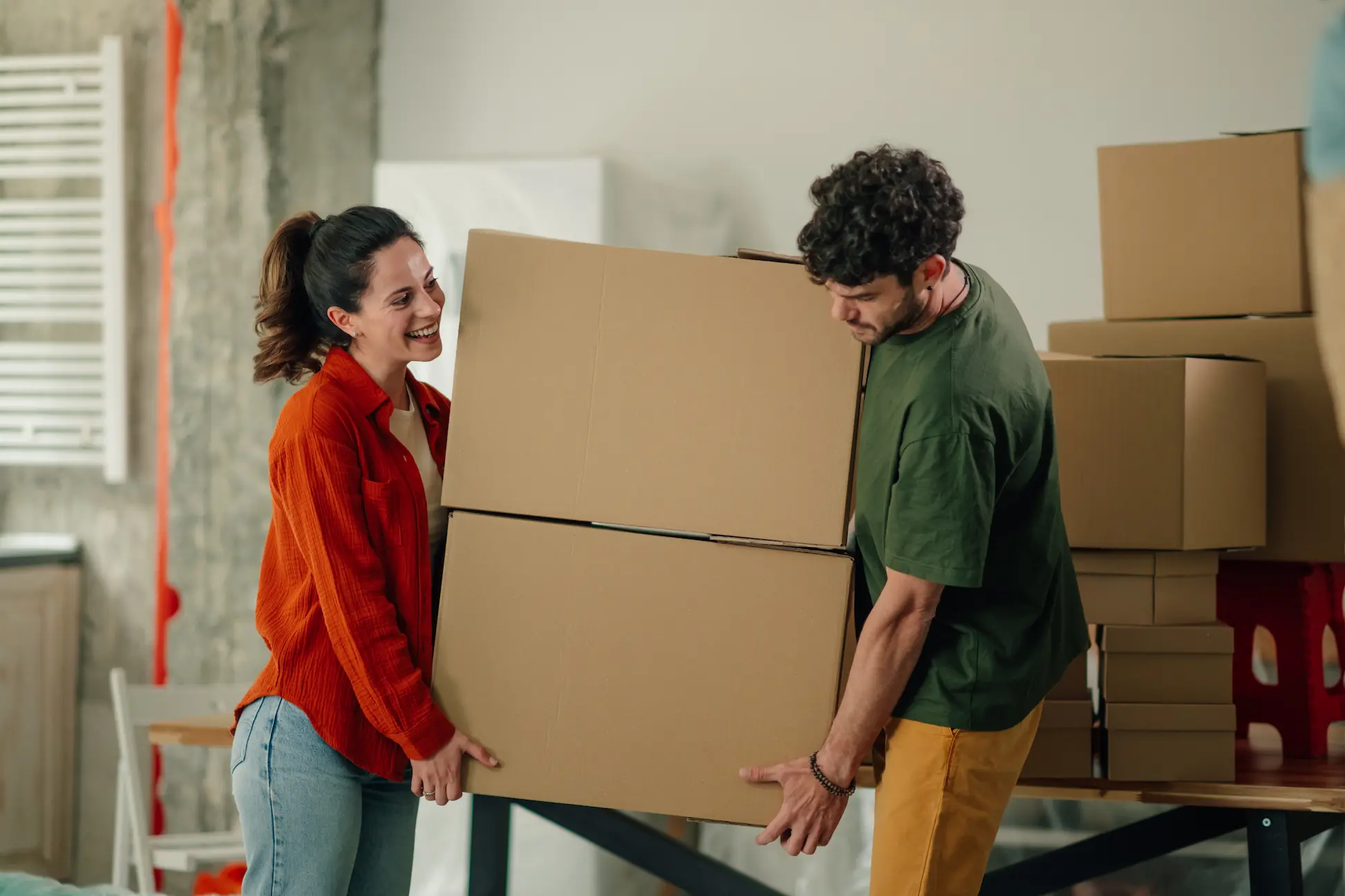 Happy couple carrying heavy cardboard boxes